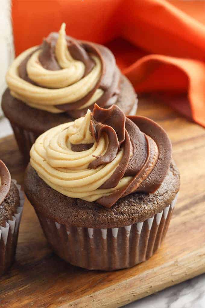 a chocolate cupcake on a cutting board with orange linen behind it