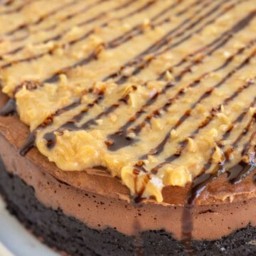 showing the topping on the german chocolate cheesecake and the side of the cheesecake sitting on a white plate