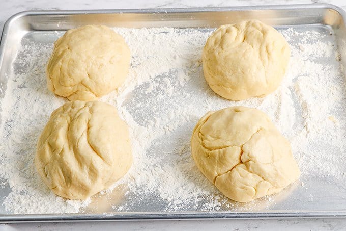 four pieces of dough on a well floured baking sheet