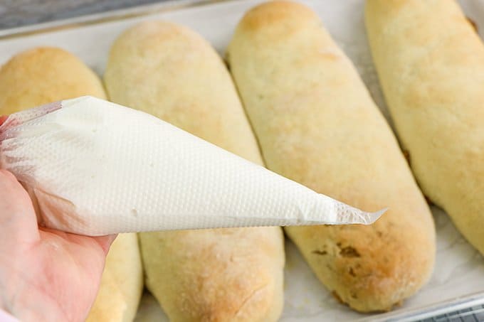 glaze in a disposable piping bag with the baked nut rolls behind it