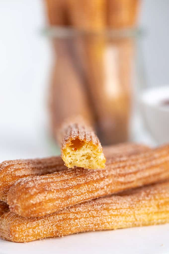 a churro broke in half to show inside sitting on top of a stack of churros