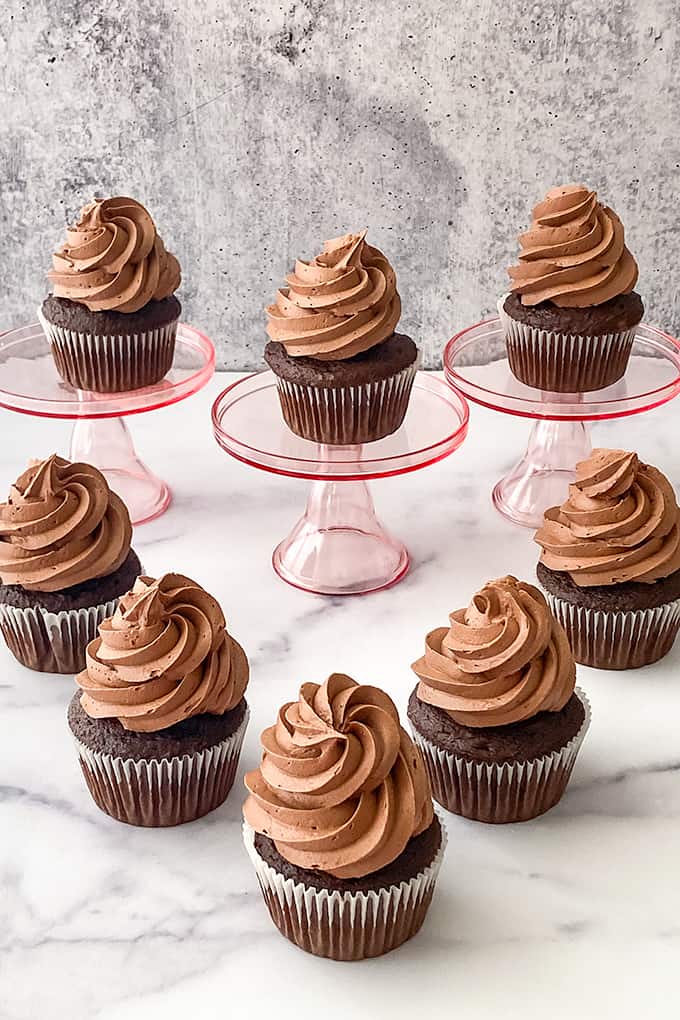 cupcakes with tall swirls of frosting on a marble surface showing the frosting