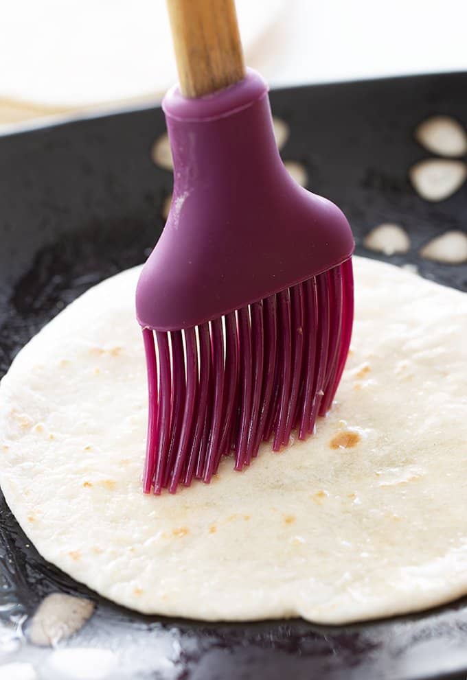 brushing a tortilla shell with butter