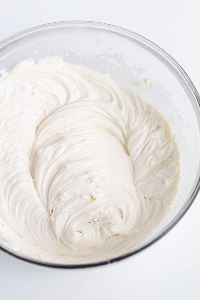 bowl of cheesecake filling in a glass bowl on a white surface