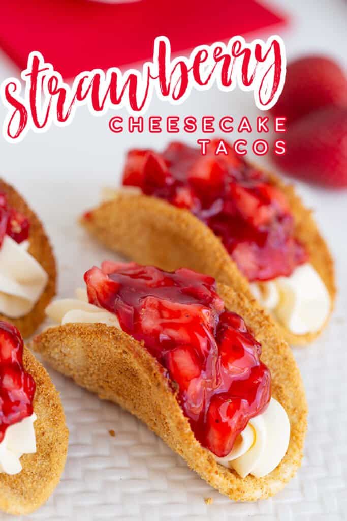 zoomed in image of the cheesecake tacos on a white board with strawberries and red fabric behind it and text at the top with the recipe name