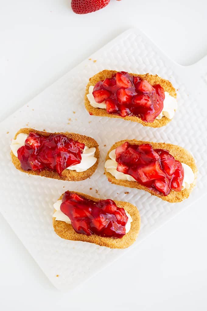 overhead of cheesecake tacos on a white cutting board and on a white surface