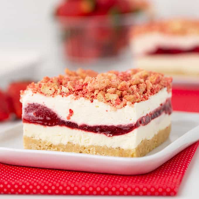 A luscious dessert with a strawberry crunch layer served on a white plate.