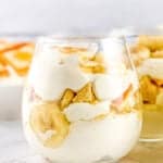 glass full of layers of banana pudding on a white surface