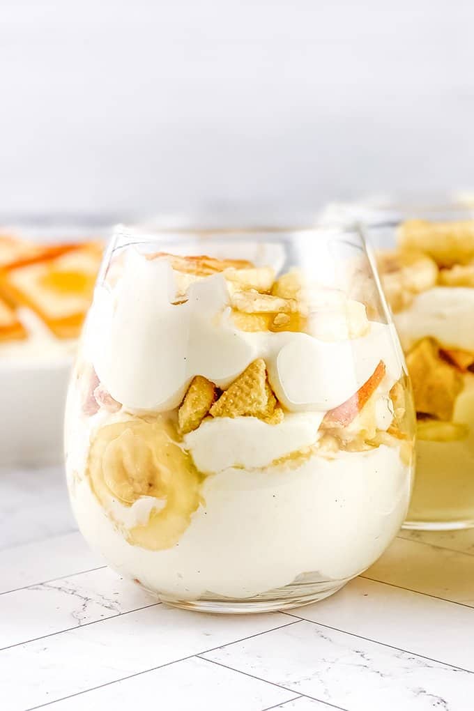 glass full of layers of banana pudding on a white surface