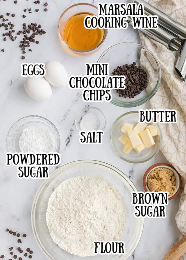 overhead photo of the cannoli shell ingredients laying out on a marble surface with what they are in text by each ingredient