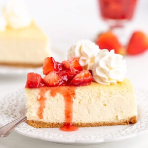 square image of a slice of cheesecake on a white plate with a fork