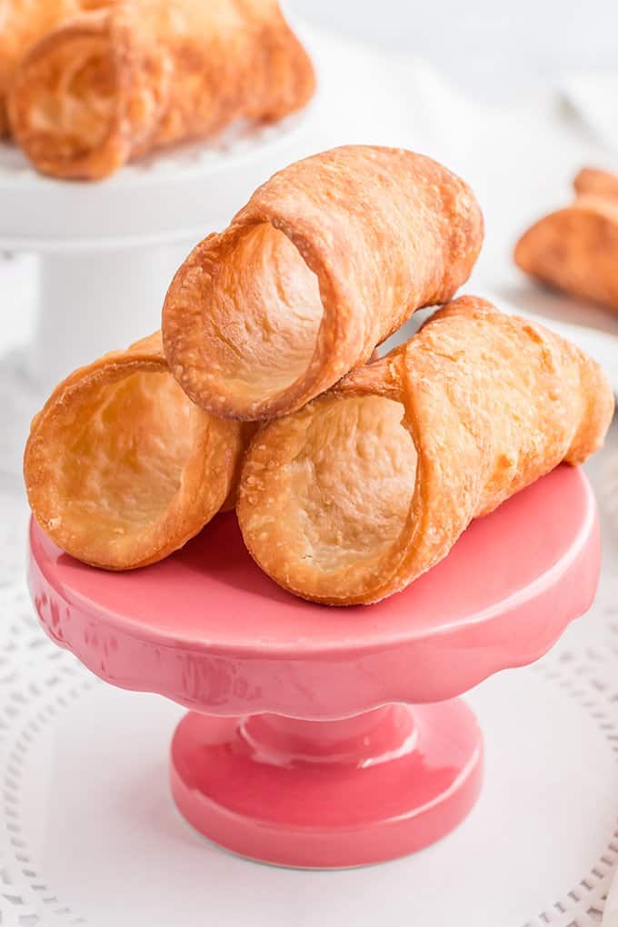 close up of cannoli shells on a small pink stand