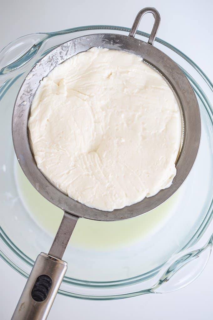ricotta in a strainer sitting on a glass bowl