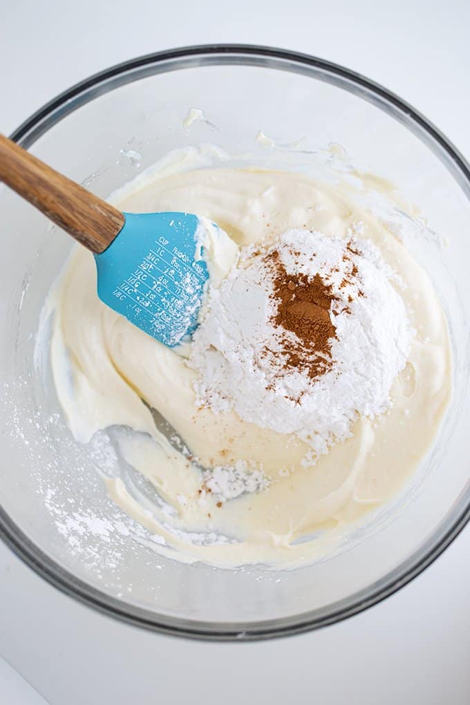 ingredients to make the cannoli filling in a glass bowl on a white surface