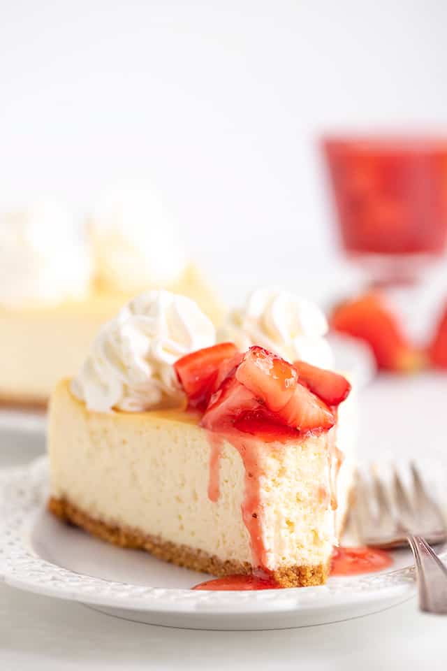 slice of cheesecake on a white plate with a bite taken out and a fork on the plate