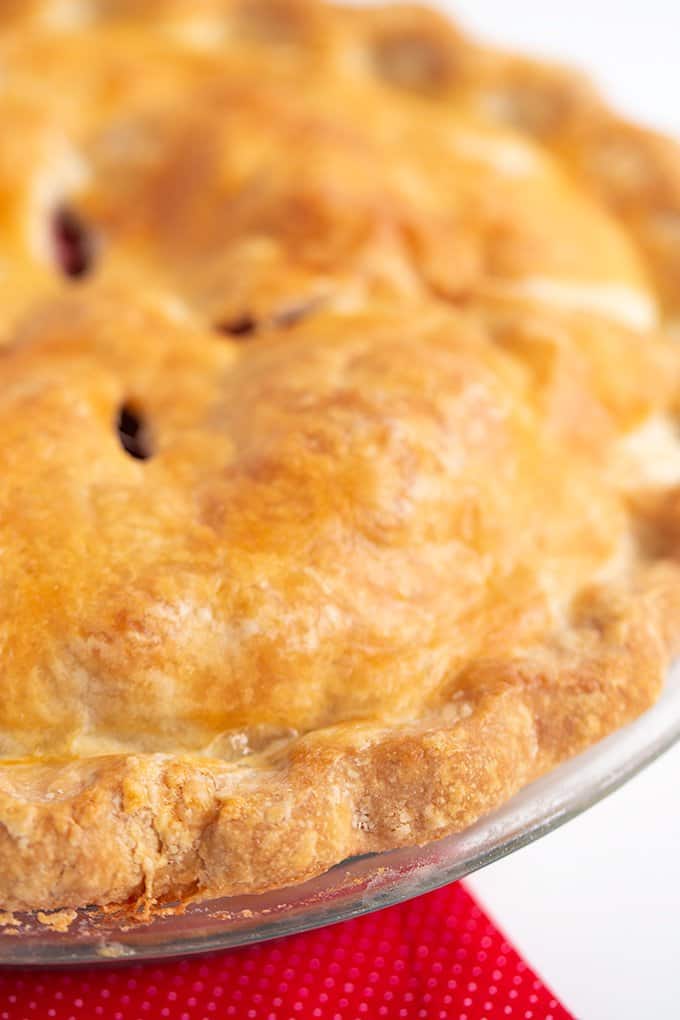 close up of the edge of a baked pie crust with a red linen under it