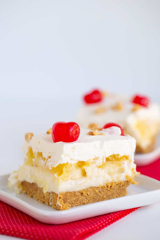 slice of banana split cake on a white square plate with a red linen under it
