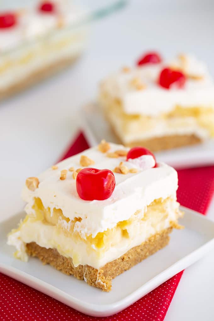 slice of banana split cake on a white plate with a red linen under it