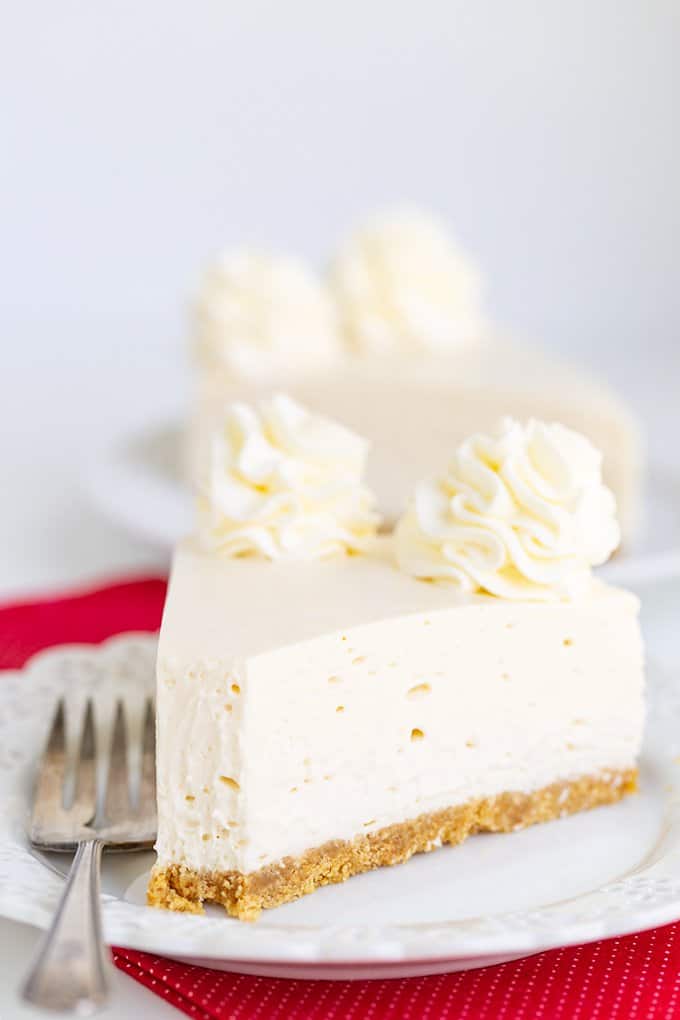 slice of cheesecake on a white plate with a bite taken out of it and a fork on the plate