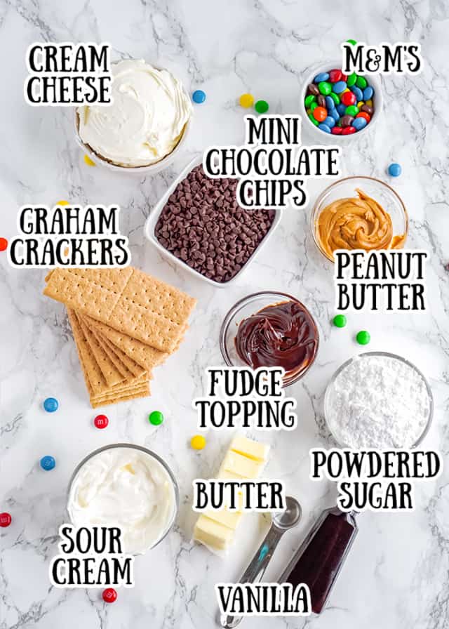 ingredients for a no bake monster cookie dough cheesecake pie laid out on a marble background