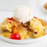 square image of the pineapple upside down dump cake with ice cream on top on a white plate