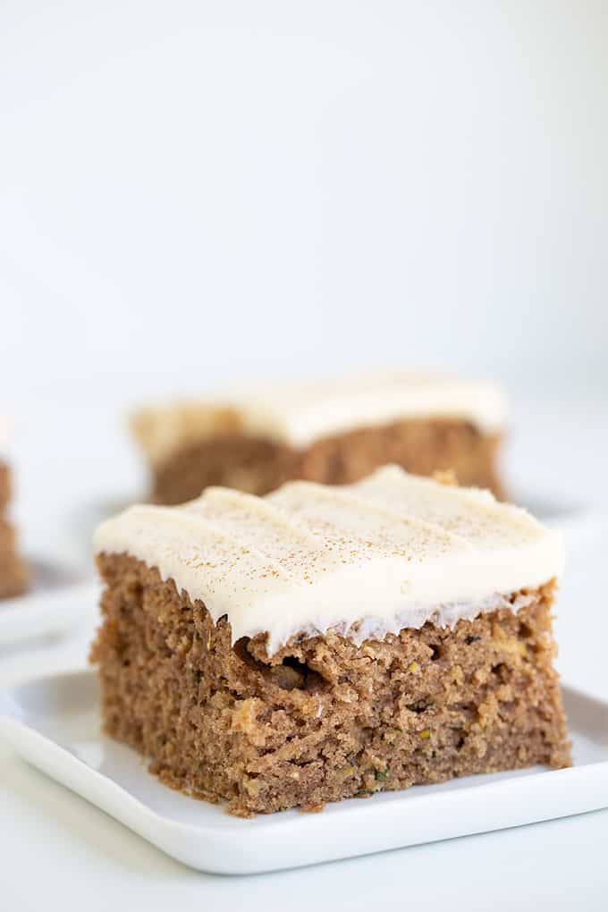 close up showing a slice of cake on a white square plate with a white background