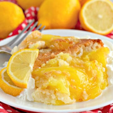 upclose picture of lemon cobbler on a white plate with fresh lemon slices and a fork