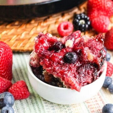 bowl of berry cobbler with a spoon and berries around it