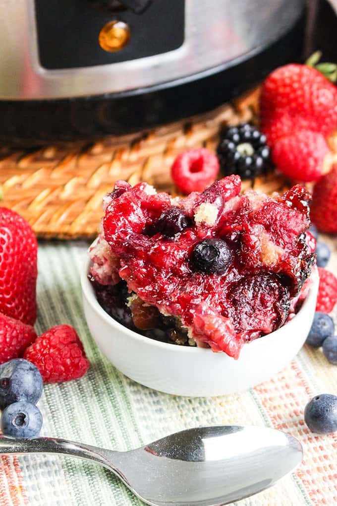 bowl of berry cobbler with a spoon and berries around it
