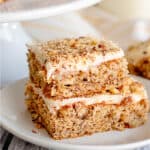 A stack of carrot cake bars with banana on a plate.