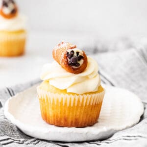 square image of cupcakes on a small textured white plate with a linen on a gray surface