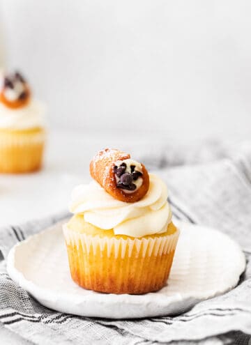 cupcakes on a white plate with a gray linen under it and a cupcake in the background