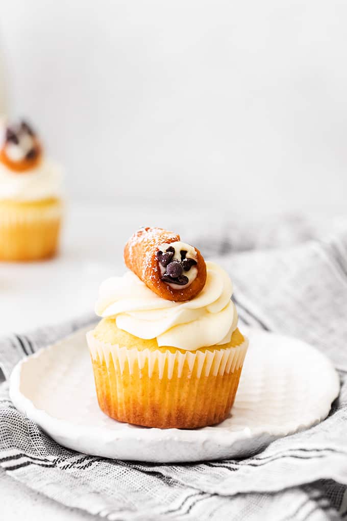 cupcakes on a white plate with a gray linen under it and a cupcake in the background