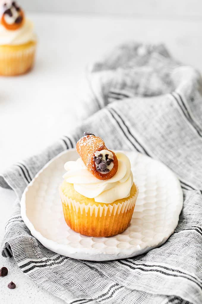 cannoli cupcakes on a small white plate with a gray linen under it