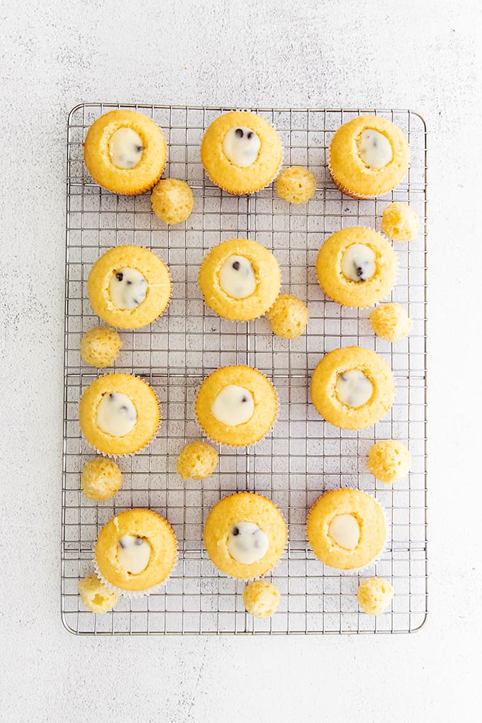 cupcakes filled with cannoli filling on a wire rack on a gray surface