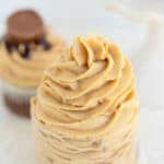 a small glass bowl filled with swirls of peanut butter frosting on a white surface