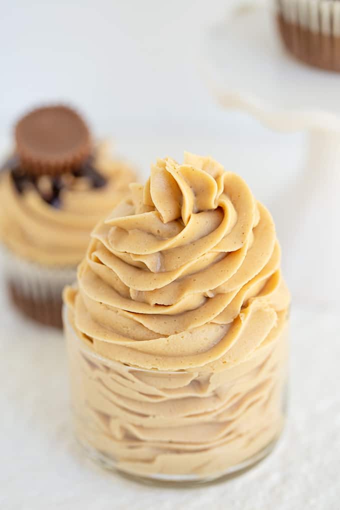 a small glass bowl filled with swirls of peanut butter frosting on a white surface