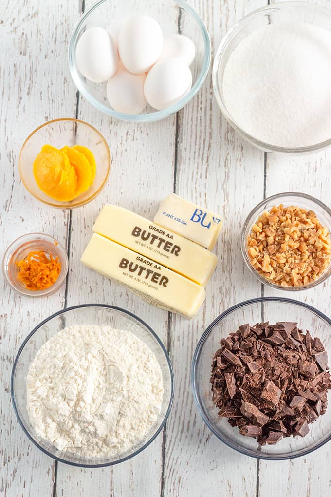 overhead photo of ingredients for chocolate orange brownies in glass bowls on a white wood surface