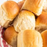 basket full of dinner rolls with a red and white linen