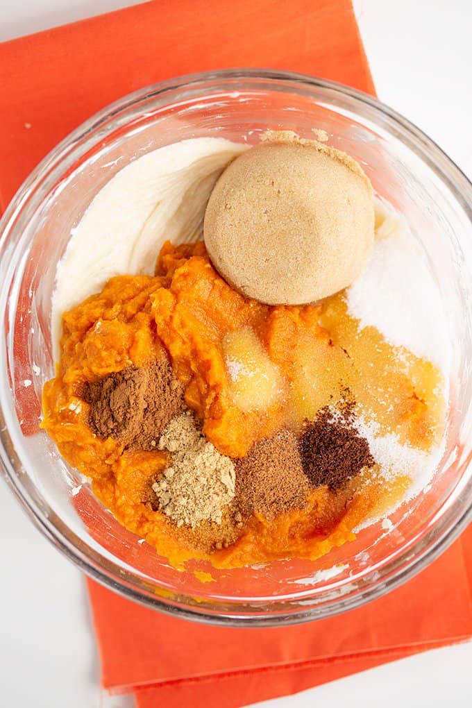 Bowl with ingredients: light brown sugar, pumpkin puree, cinnamon, ginger, cloves, nutmeg, salt, and cream cheese.