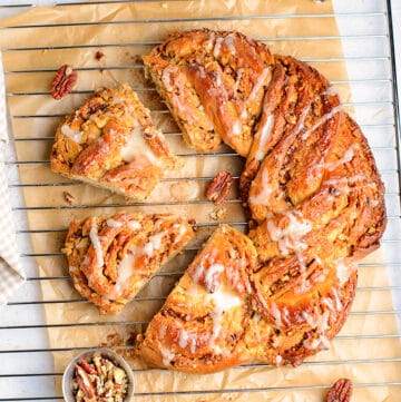 whole maple pecan bread with slices cut on a wire rack with parchment paper under it