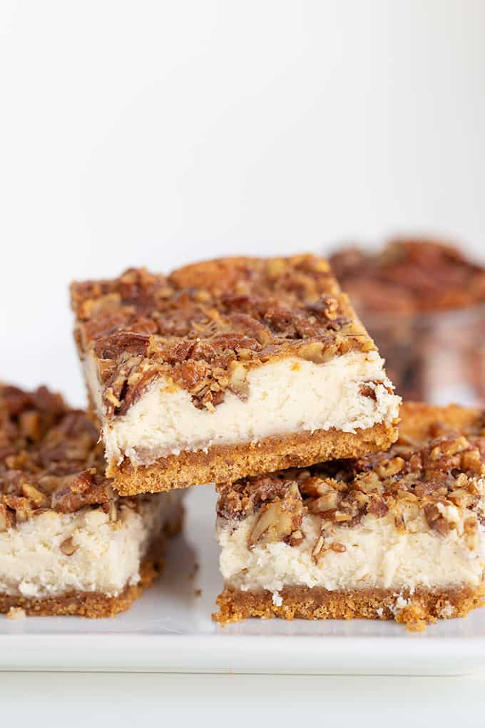 stacked bars on a white plate with pecans behind the bars