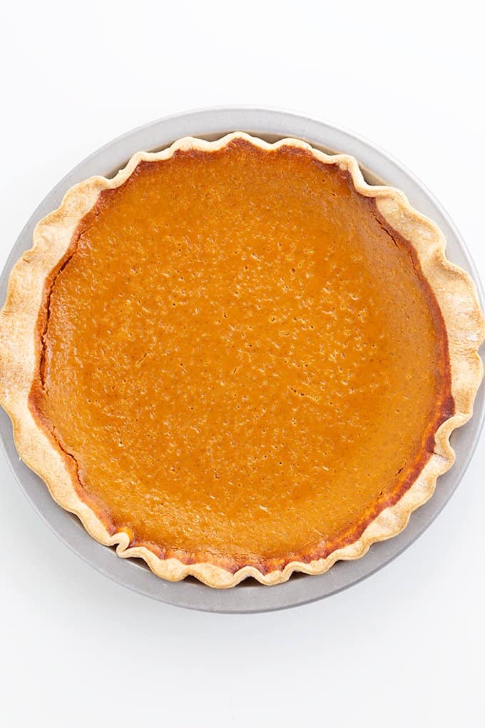 overhead image of the whole pumpkin pie on a white surface