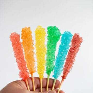 hand holding the rock candy with a white surface behind it