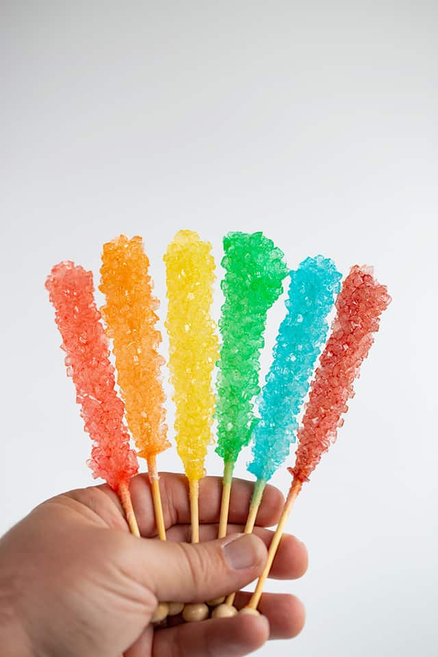 hand holding the rock candy with a white surface behind it