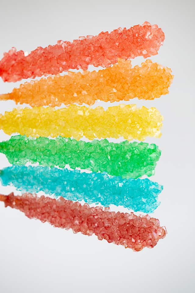 holding sticks of rock candy in the air with a white background