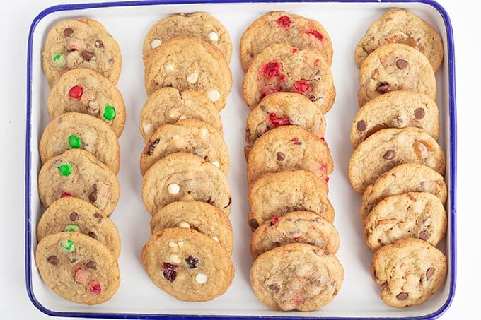 overhead image of a variety of chocolate chip cookies on a blue rimmed white enamel sheet