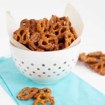 white bowl with candied pretzels in it with a light blue linen on a white surface