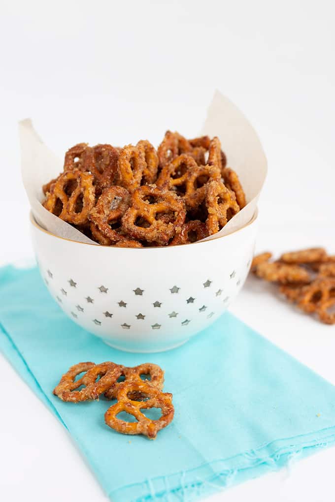 white bowl with candied pretzels in it with a light blue linen on a white surface