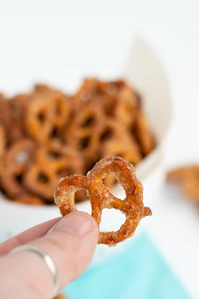 fingers holding a pretzel in front of the bowl of pretzels